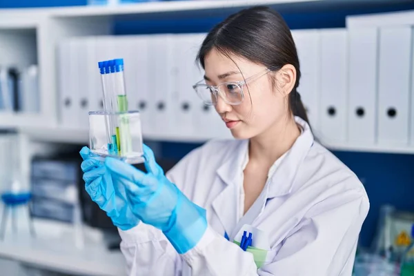 Chinese woman scientist holding test tubes at laboratory