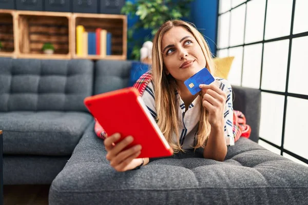 Young Blonde Woman Using Touchpad Credit Card Lying Sofa Home — Stock fotografie