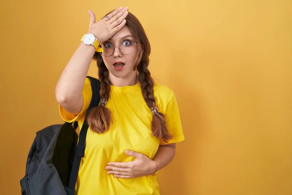 Młoda Kaukaska Kobieta Nosząca Plecak Studencki Żółtym Tle Zaskoczona Pomyłką — Zdjęcie stockowe
