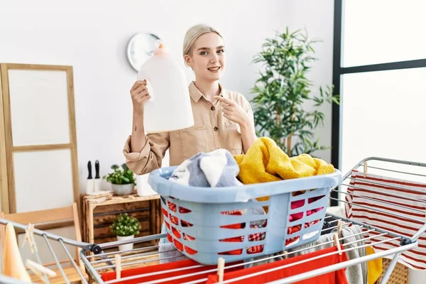 Joven Mujer Caucásica Haciendo Lavandería Sosteniendo Botella Detergente Sonriendo Feliz —  Fotos de Stock