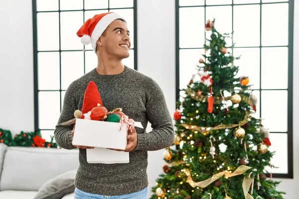 Молодий Іспаномовний Чоловік Посміхається Впевнено Тримає Коробку Різдвяним Прикрасою Вдома — стокове фото
