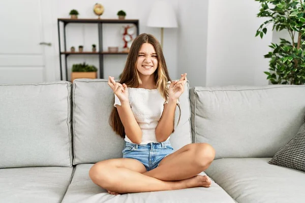 Ung Brunett Tonåring Sitter Soffan Hemma Gestikulerande Finger Korsade Leende — Stockfoto