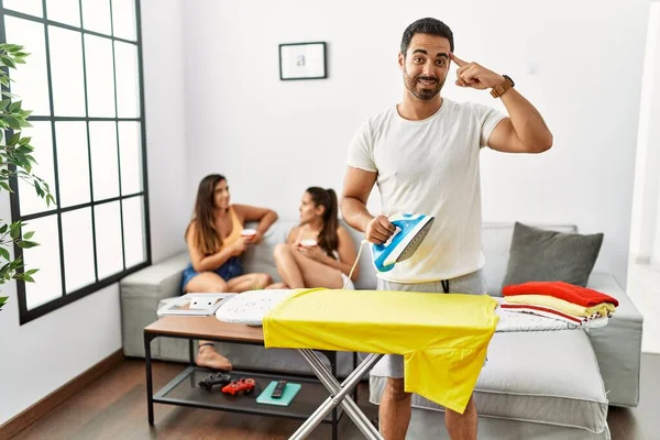 Giysilerini ütüleyen genç İspanyol adam gülümseyerek tek parmağıyla kafasını işaret ediyor, harika bir fikir ya da düşünce, iyi bir hafıza. 