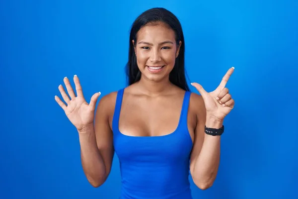 Mavi Arka Planda Duran Spanyol Kadın Yedinci Parmaklarını Gösterip Işaret — Stok fotoğraf