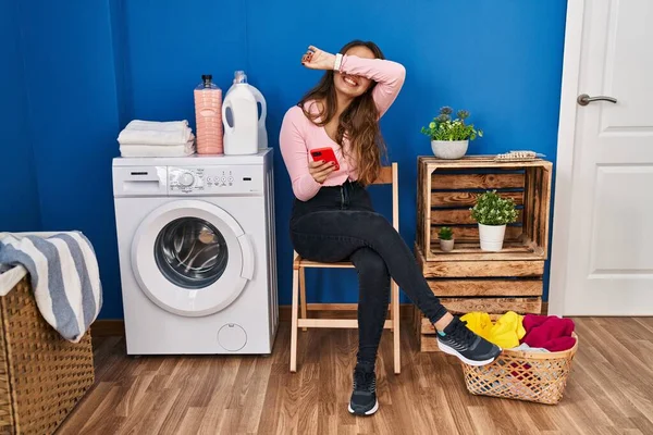 Genç İspanyol kadın çamaşırlarını yıkamak için bekliyor. Akıllı telefon kullanıyor. Gülümsüyor, gülümsüyor. Şaşırdım ve çıktım. 