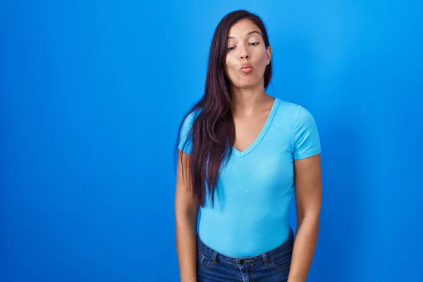 Junge Hispanische Frau Steht Vor Blauem Hintergrund Und Macht Fischgesicht — Stockfoto