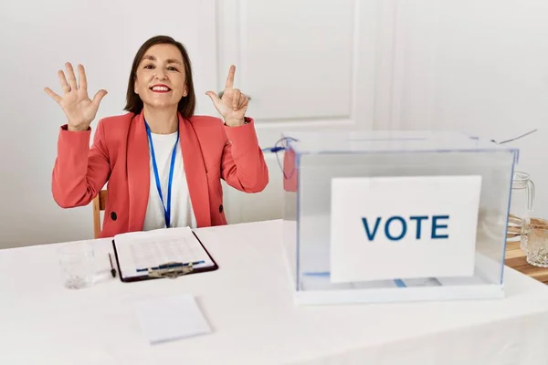 自信と幸せを笑顔ながら指の番号7を示し 指差す投票によって座っている政治選挙で美しい中世のヒスパニック女性 — ストック写真