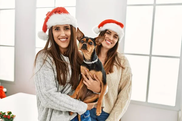 Δύο Γυναίκες Χαμογελώντας Αυτοπεποίθηση Αγκαλιάζει Σκυλί Στέκεται Από Χριστουγεννιάτικη Διακόσμηση — Φωτογραφία Αρχείου