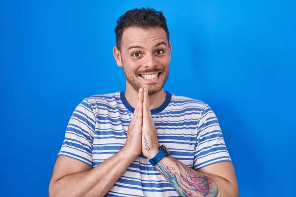 Joven Hombre Hispano Pie Sobre Fondo Azul Rezando Con Las — Foto de Stock