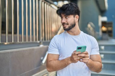 Sokakta akıllı telefon kullanan, kendine güvenen genç bir İspanyol.