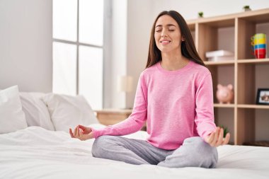 Genç ve güzel İspanyol kadın yoga yapıyor. Yatak odasında oturuyor.