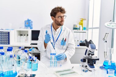 Laboratuvarda çalışan, bilim adamı üniforması giyen İspanyol genç adam.