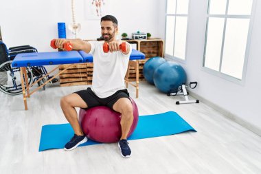 Genç İspanyol hasta, rehabilitasyon seansında sağlıklı top ve dambıllarla gülümsüyor.