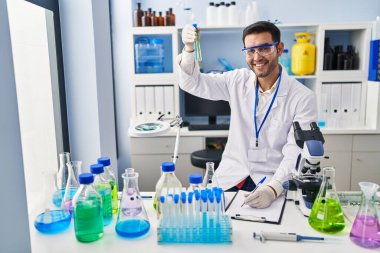 Laboratuvarda test tüpleri tutan genç İspanyol bilim adamı rapor yazıyor.