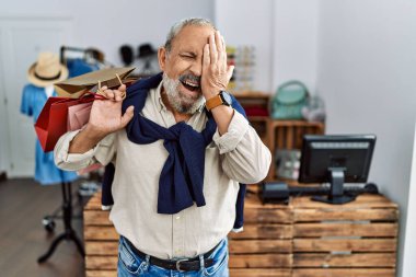 Yakışıklı son sınıf öğrencisi butik dükkanında alışveriş torbaları tutuyor. Bir gözünü eliyle kapatıyor. Yüzünde kendine güvenen bir gülümseme ve sürpriz bir duygu var.. 