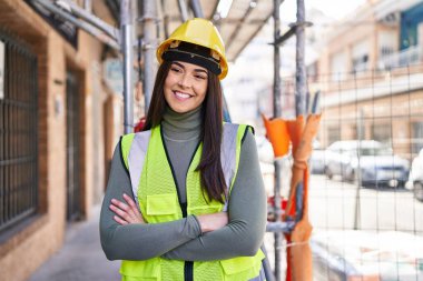 Güzel İspanyol kadın mimar gülümsüyor. Kollarını kavuşturup caddede duruyor.