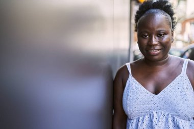 Genç Afrikalı Amerikalı kadın gülümseyerek şehirde mutlu mesut duruyor..