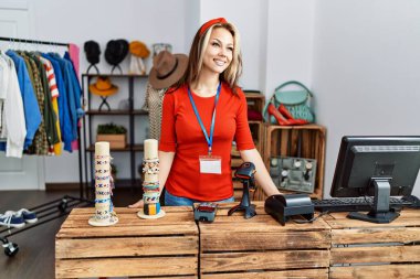 Giyim mağazasında çalışırken gülümseyen beyaz bir kadın..