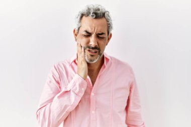 Orta yaşlı İspanyol bir adam tecrit edilmiş arka planda durup diş ağrısı ya da diş hastalığından dolayı ağıza acı dolu bir ifadeyle dokunuyor. dişçi 