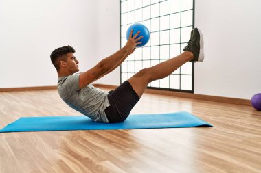 Spor merkezinde top kullanarak karın kaslarını çalıştıran genç bir İspanyol.