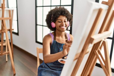 Sanat stüdyosunda müzik dinleyen genç Afrikalı Amerikalı kadın.