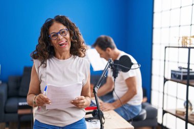 Orta yaşlı İspanyol kadın müzik stüdyosunda şarkı söylüyor. Dilini komik bir ifadeyle dışarı çıkarıyor.. 