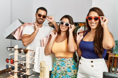 Bir grup İspanyol gülümseyen insan elbise mağazasında güneş gözlüğü denerken mutlu olurlar..