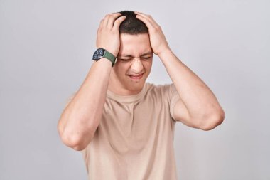 İzole edilmiş arka planda duran genç adam baş ağrısı, çaresiz ve stresli çünkü acı ve migren. Eller başının üstünde.. 