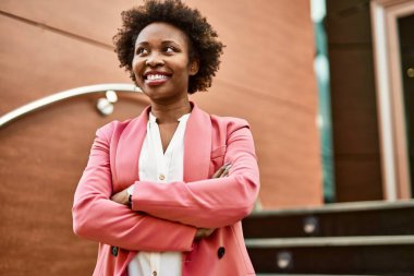 Güzel bir iş adamı Afro saçlı Amerikalı kadın şehirde mutlu ve kendinden emin bir şekilde gülümsüyor.
