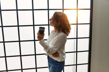 Olgun İspanyol kadın ofiste kahve içiyor.