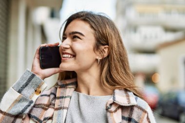 Sokakta akıllı telefondan konuşan genç sarışın kadın.