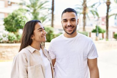 Genç Latin çift gülümsüyor ve şehirde sarılıyorlar..