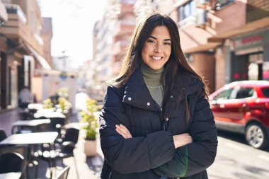 Sokakta kollarını kavuşturmuş genç, güzel İspanyol bir kadın.