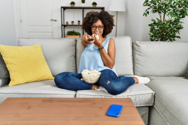 Genç Afro-Amerikan kadın gülümsüyor. Evde film izlerken kendine güveniyor.