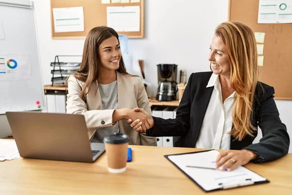 Mother and daughter business workers smiling confident shake hands at office