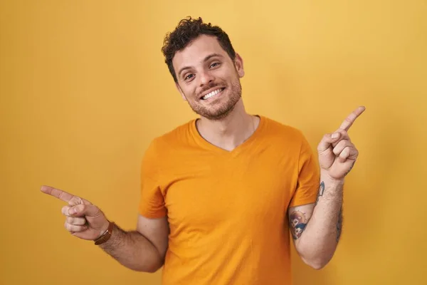 Joven Hombre Hispano Pie Sobre Fondo Amarillo Sonriendo Confiado Señalando —  Fotos de Stock