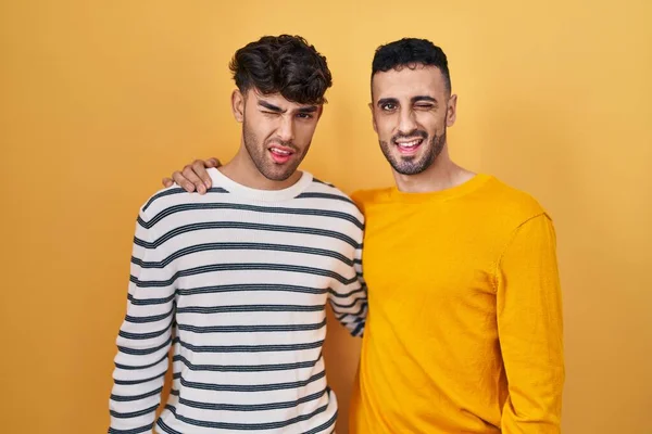 Unga Latinamerikanska Homosexuella Par Står Över Gul Bakgrund Blinkar Tittar — Stockfoto