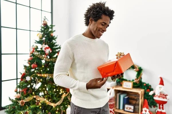 Joven Afroamericano Hombre Sosteniendo Regalo Pie Junto Árbol Navidad Casa —  Fotos de Stock