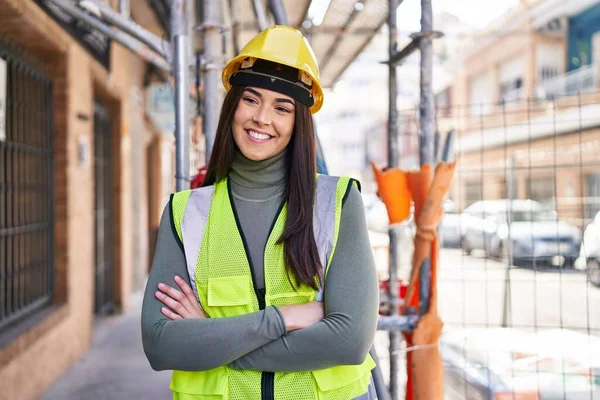 Güzel İspanyol kadın mimar gülümsüyor. Kollarını kavuşturup caddede duruyor.
