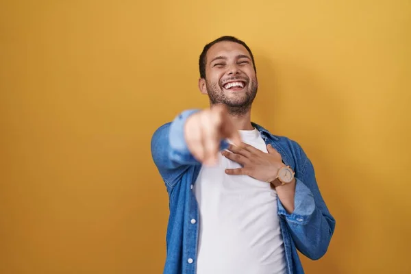 Латиноамериканець Стоїть Над Жовтим Фоном Сміється Вказуючи Пальцем Камеру Рукою — стокове фото