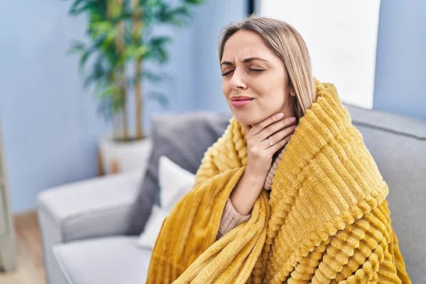 Young woman suffering for throat pain sitting on sofa at home
