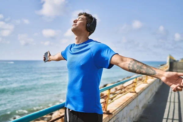 Ung Latinamerikansk Man Andas Med Hörlurar Och Smartphone Stranden — Stockfoto