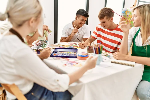 アートスタジオのテーブルに座って笑顔の人々のグループ — ストック写真
