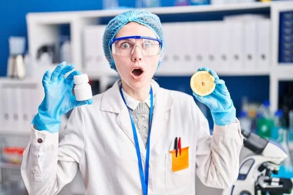 Beautiful Woman Working Scientist Laboratory Holding Pills Lemon Afraid Shocked — Stock Photo, Image