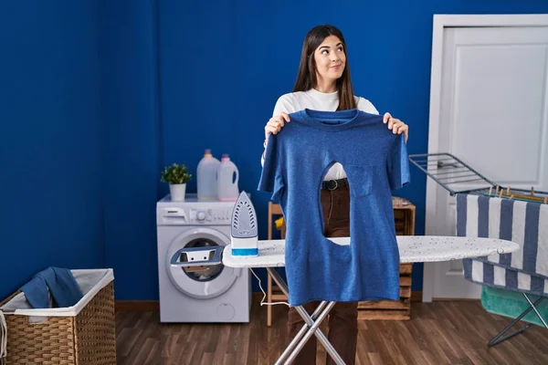 Çamaşır odasında ütü yapan genç esmer kadın. Elinde yanmış demir gömleği vardı. Gülümsüyor ve başka tarafa bakıyordu.. 