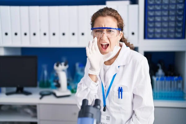 Young caucasian woman working at scientist laboratory clueless and confused with open arms, no idea and doubtful face.