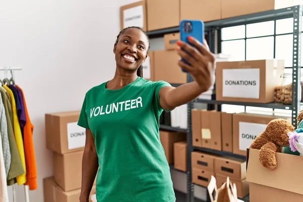 年轻的非洲裔美国女志愿者在慈善中心用智能手机高兴地做出了自己的贡献 — 图库照片