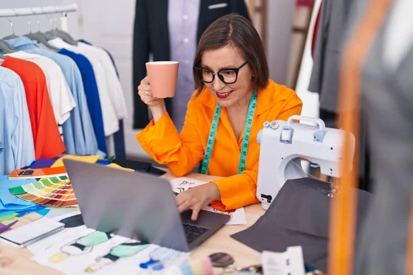 中年妇女裁缝在裁缝店用笔记本电脑喝咖啡 — 图库照片