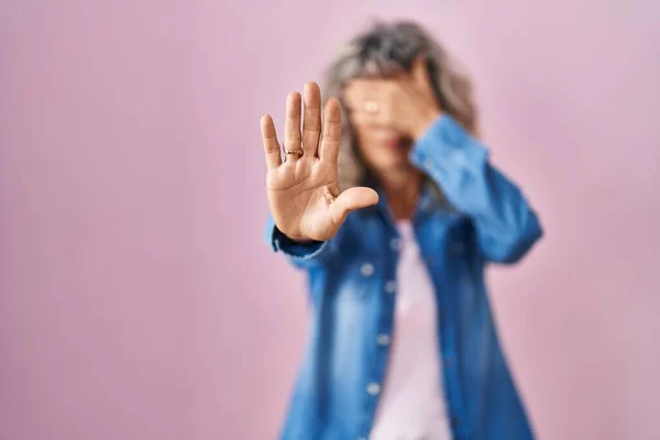 中年妇女站在粉红的背景上 用手捂住眼睛 用悲伤和恐惧的表情做停止动作 尴尬和消极的概念 — 图库照片