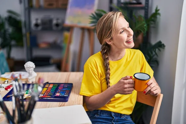 Młoda Blondynka Artystka Pije Kawę Siedząc Podłodze Studio Sztuki — Zdjęcie stockowe